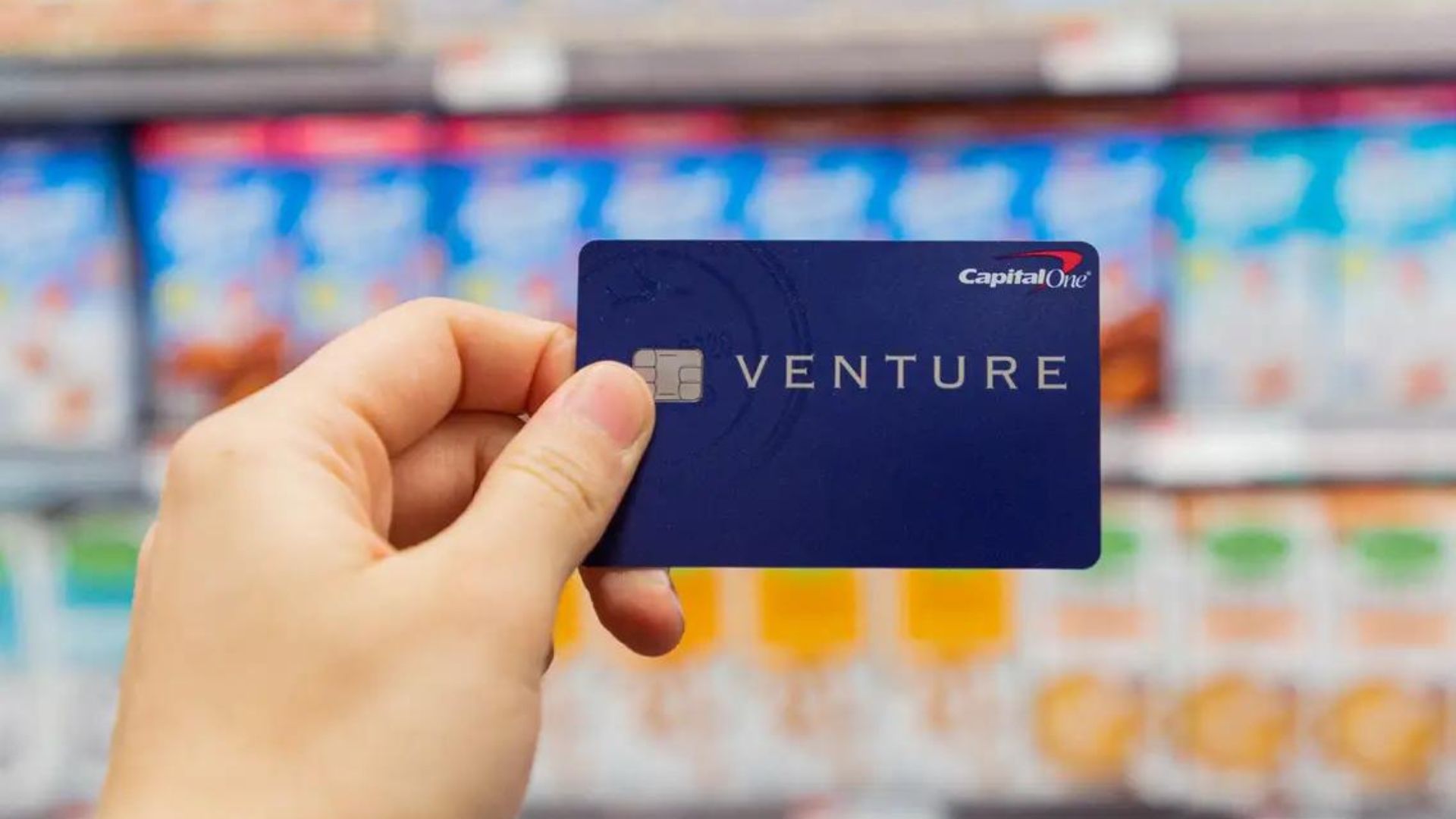 A Person holding a blue credit card in a grocery shop